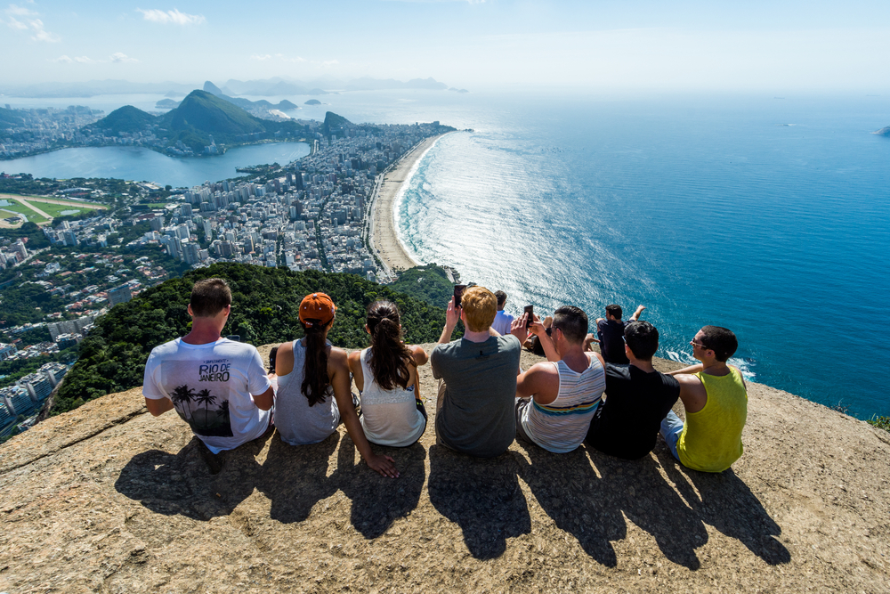 Vemos um grupo de jovens, entre homens e mulheres, na Pedra do Telégrafo, no Rio de Janeiro (imagem ilustrativa).