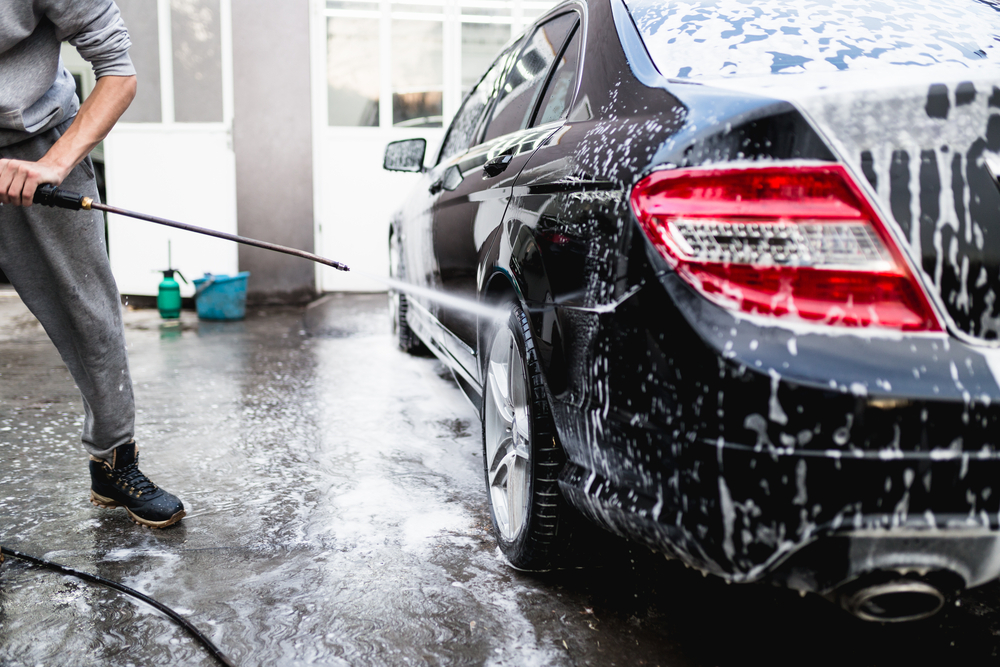 profissional fazendo a limpeza de um carro com jatos de água.